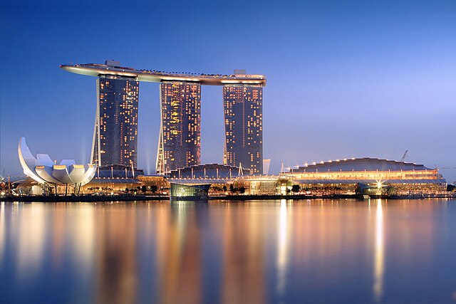 Marina Bay Sands in Singapore illuminated at night with reflections on the water.